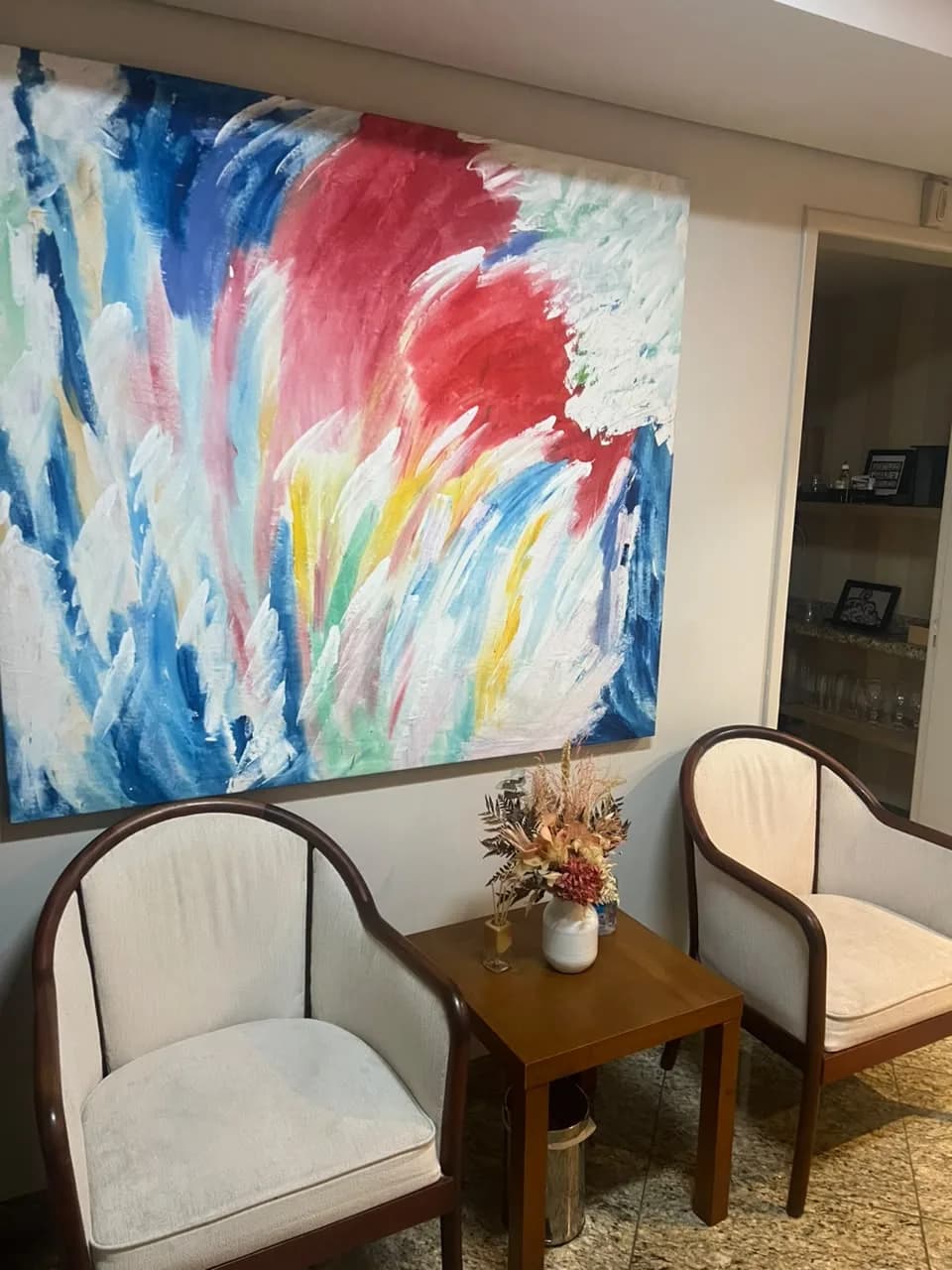 Recepção do consultório em Alphaville, com quadro colorido e poltronas de espera
