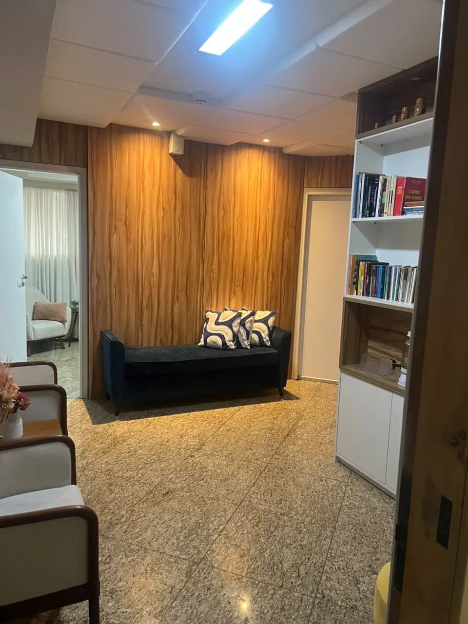Sala de espera do consultório em Alphaville, Barueri, com sofá e painel de madeira